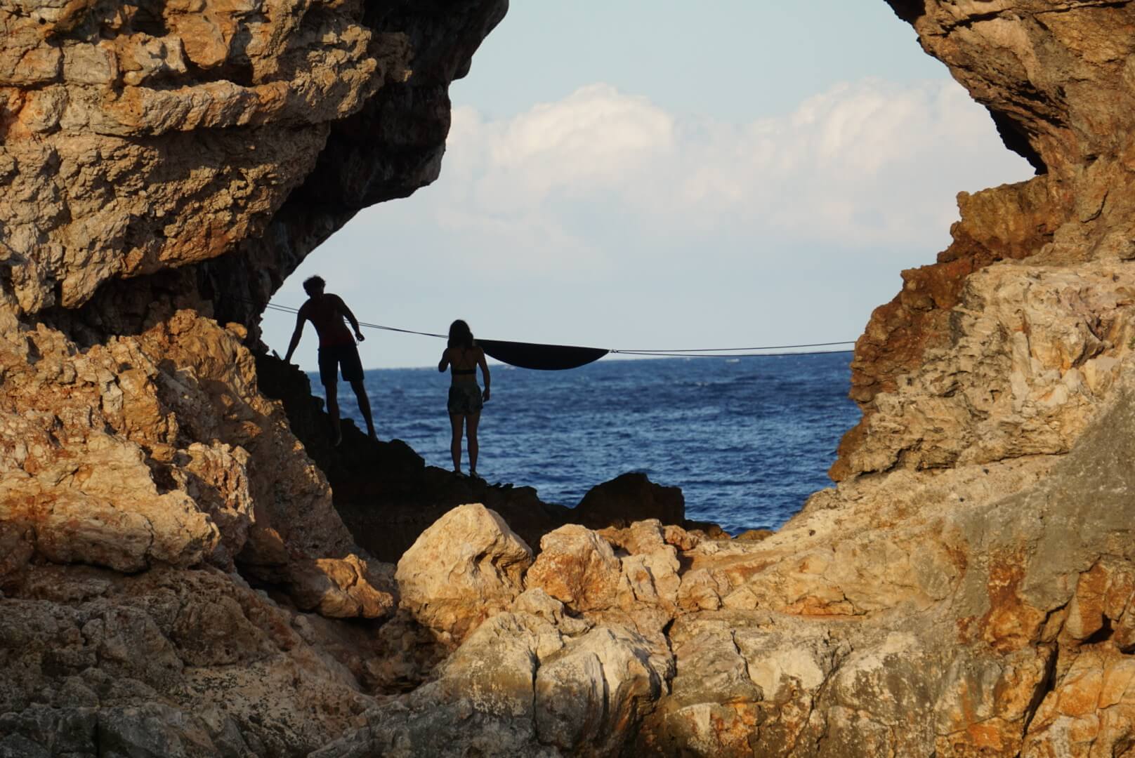 Blick durch ein Felsloch aufs Meer mit Hängematten