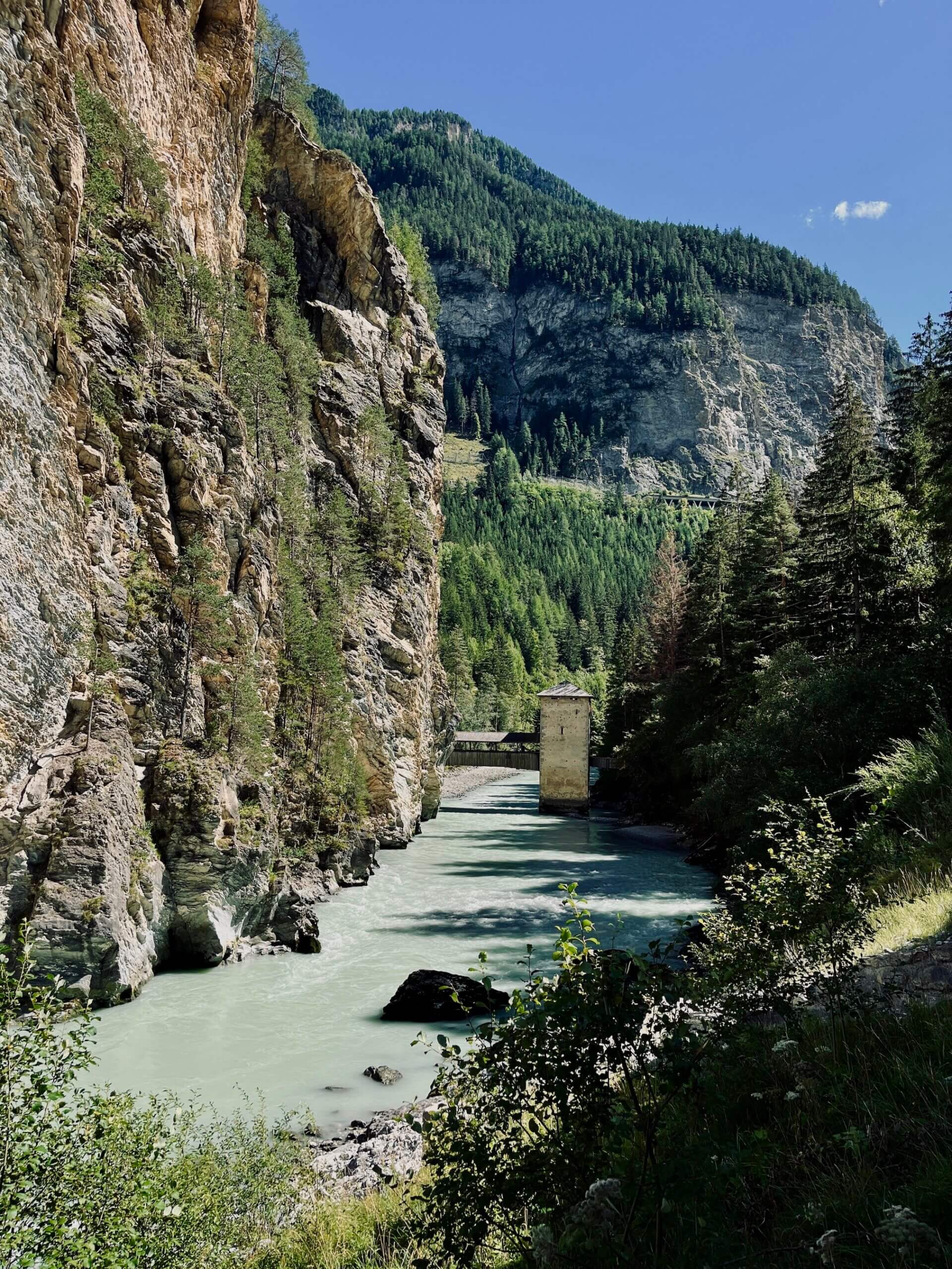 Der Inn fließt zwischen Felswänden auf der einen Seite und Waldböschung auf der anderen Seite dahin