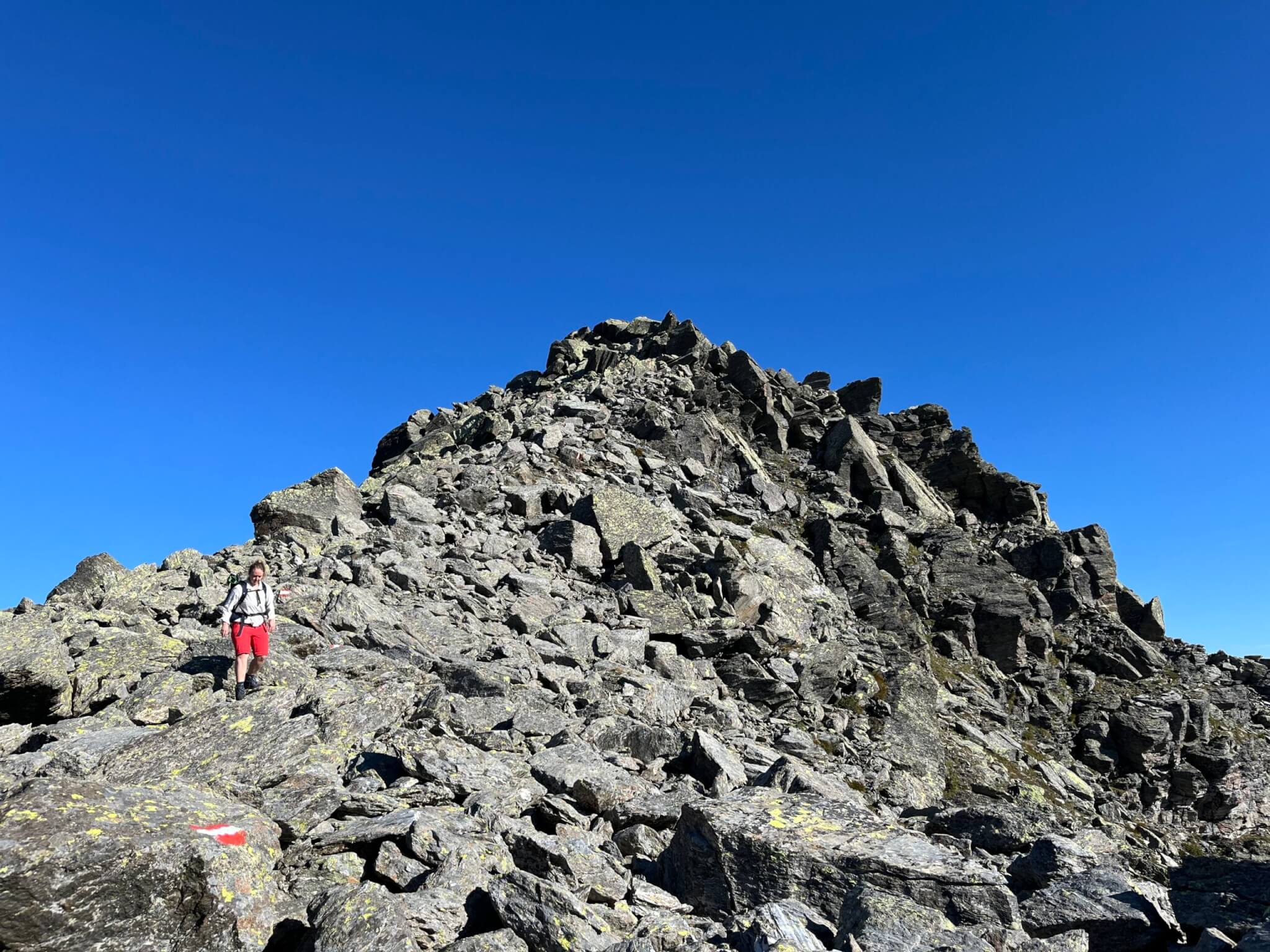Elisabeth wandert auf steinigem Untergrund am Berggipfel
